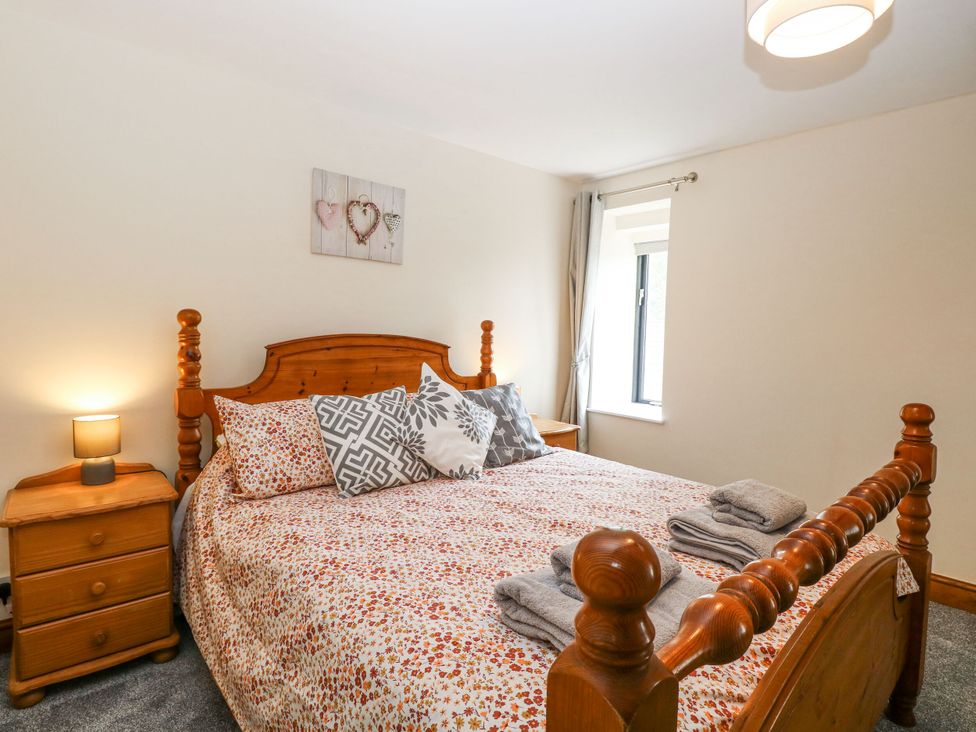 A bedroom with a bed and bedside table at Lakeside Barn Aylsham