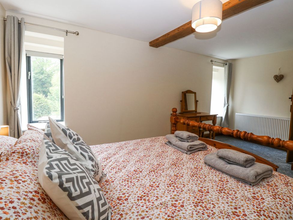 A bedroom with a bed and dressing table at Lakeside Barn in Aylsham