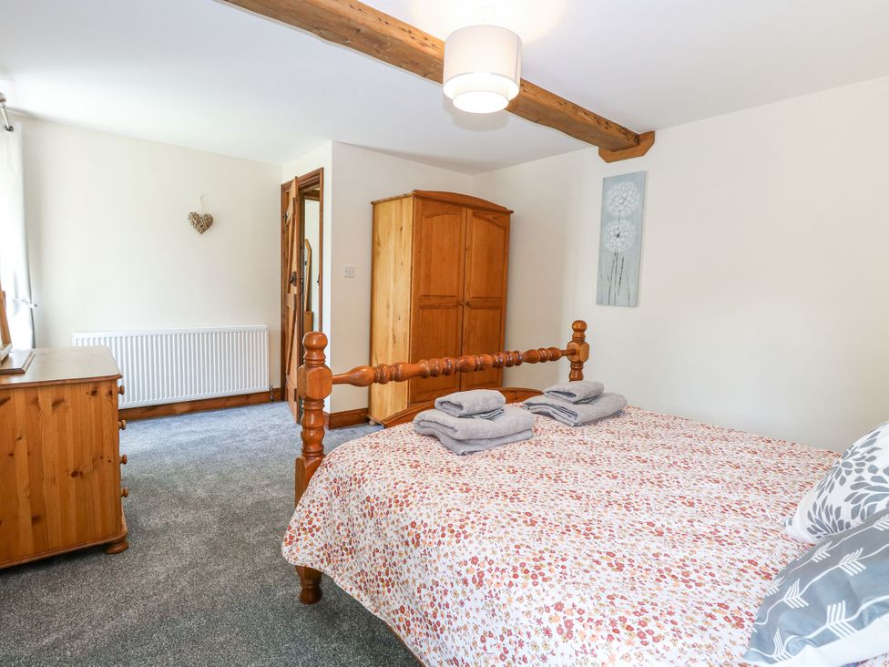 A bedroom with a bed and wardrobe at Lakeside Barn Aylsham
