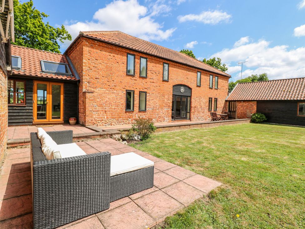 A house with a patio and a sofa at Lakeside Barn Aylsham