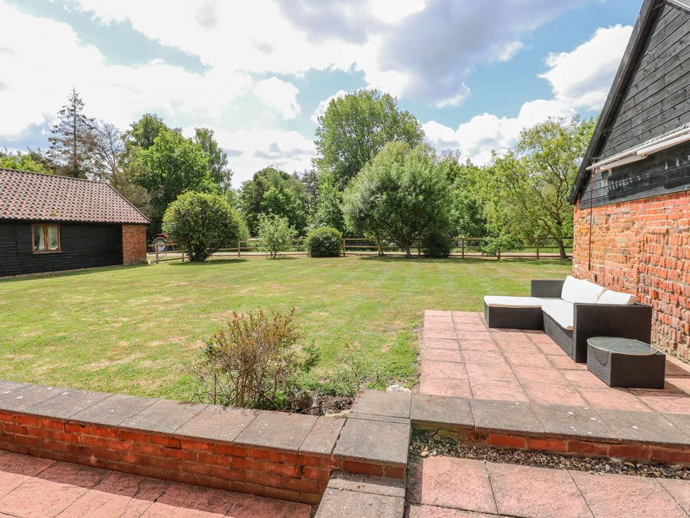 A garden with grass and patio furniture at Lakeside Barn Aylsham