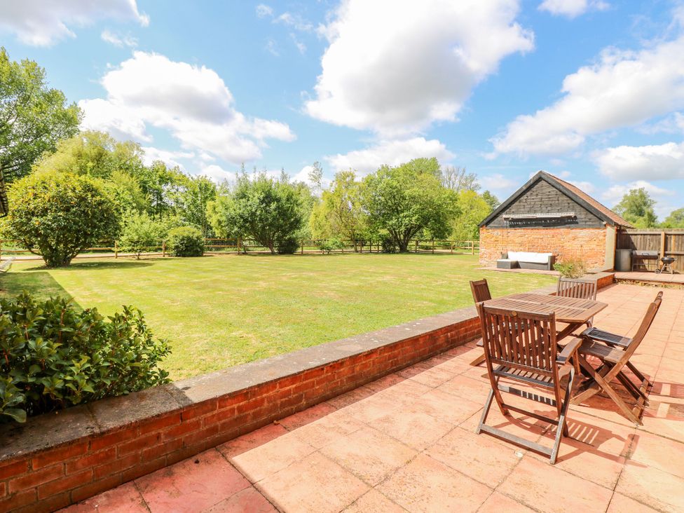 A garden with a patio area and a shed at Lakeside Barn in Aylsham