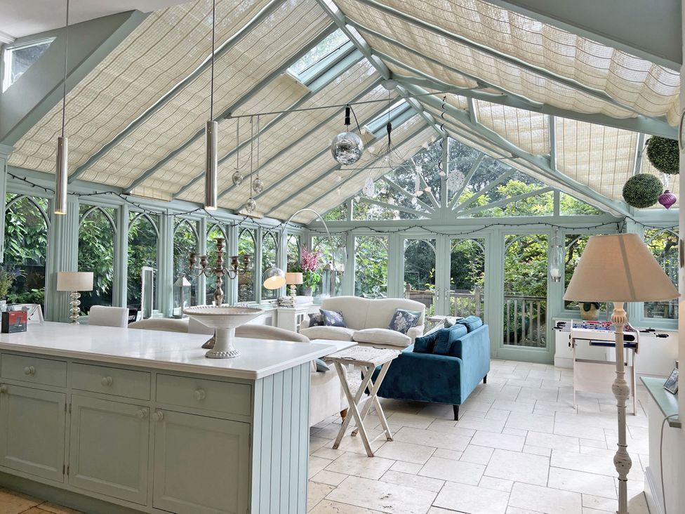 A conservatory with a kitchen island and seating area at Trenare in Truro