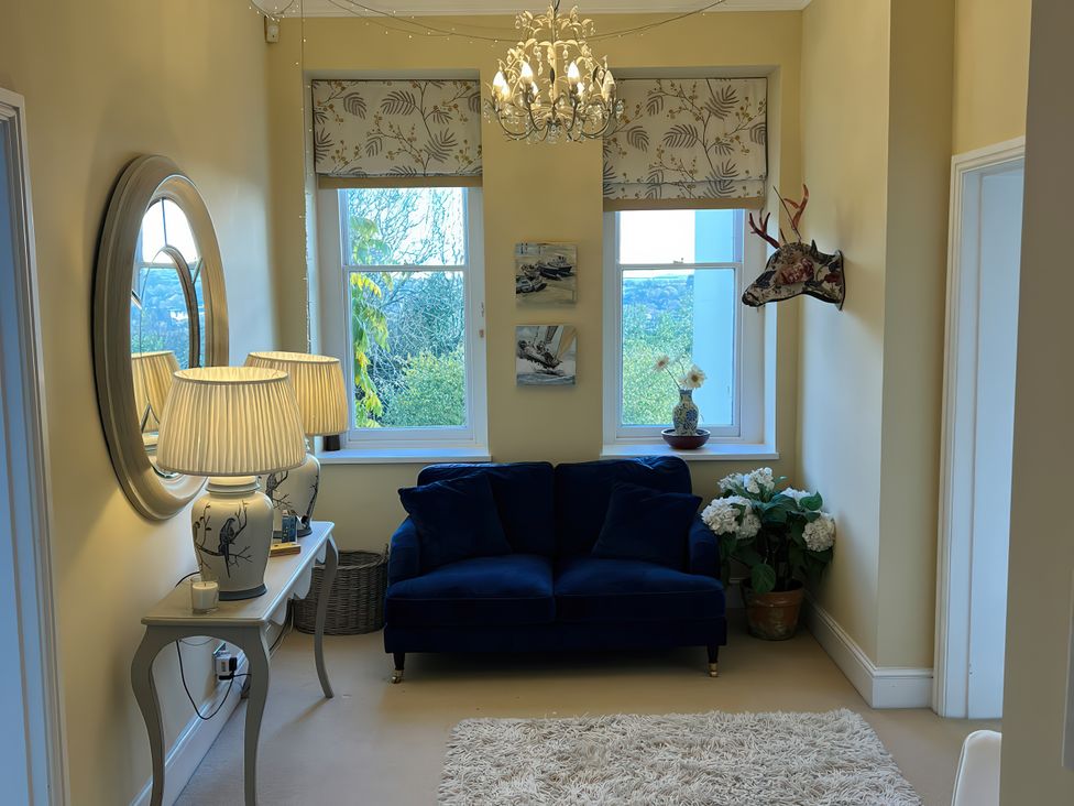 A living room with a blue sofa and chandelier at Trenare in Truro