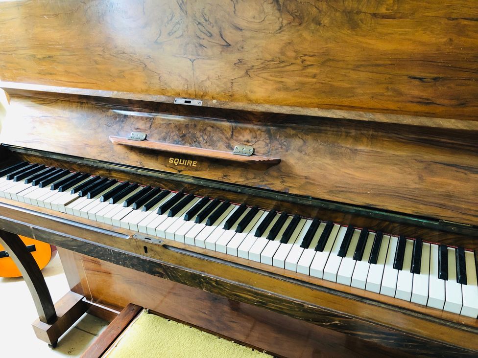A piano with wooden finish and keys in a music room at Trenare in Truro