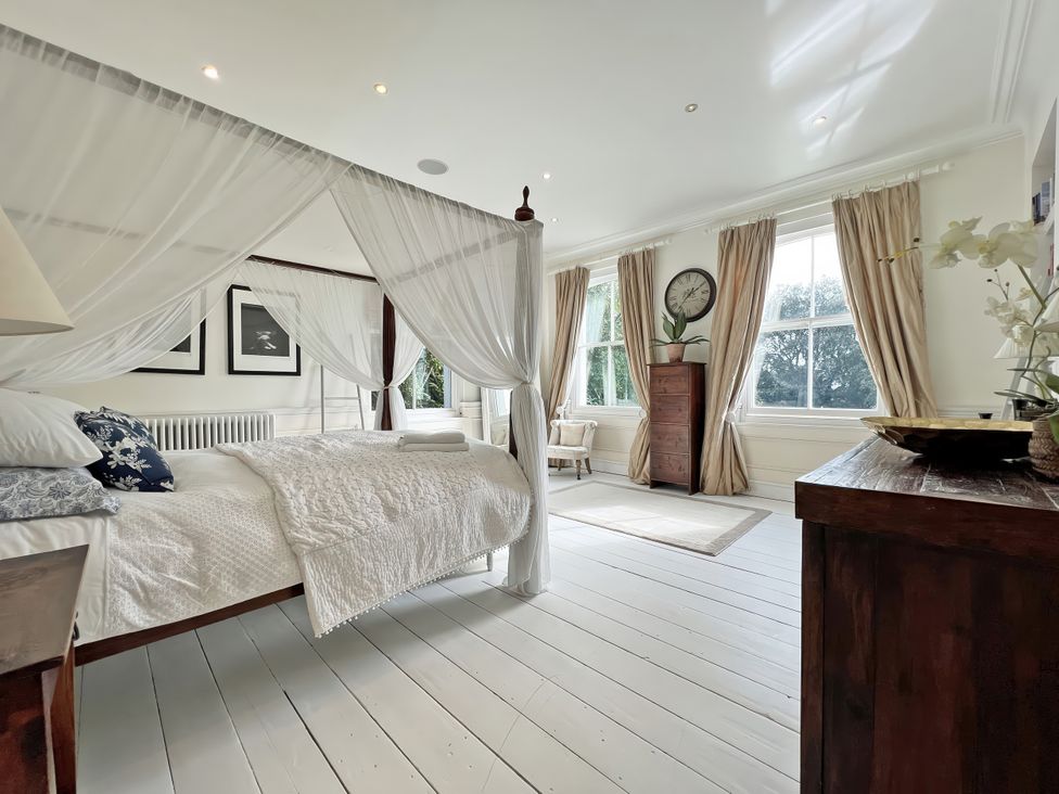 A bedroom with a canopy bed and windows at Trenare in Truro