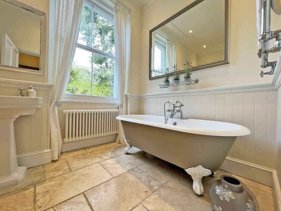 A bathroom with a bathtub, sink, and mirror at Trenare in Truro