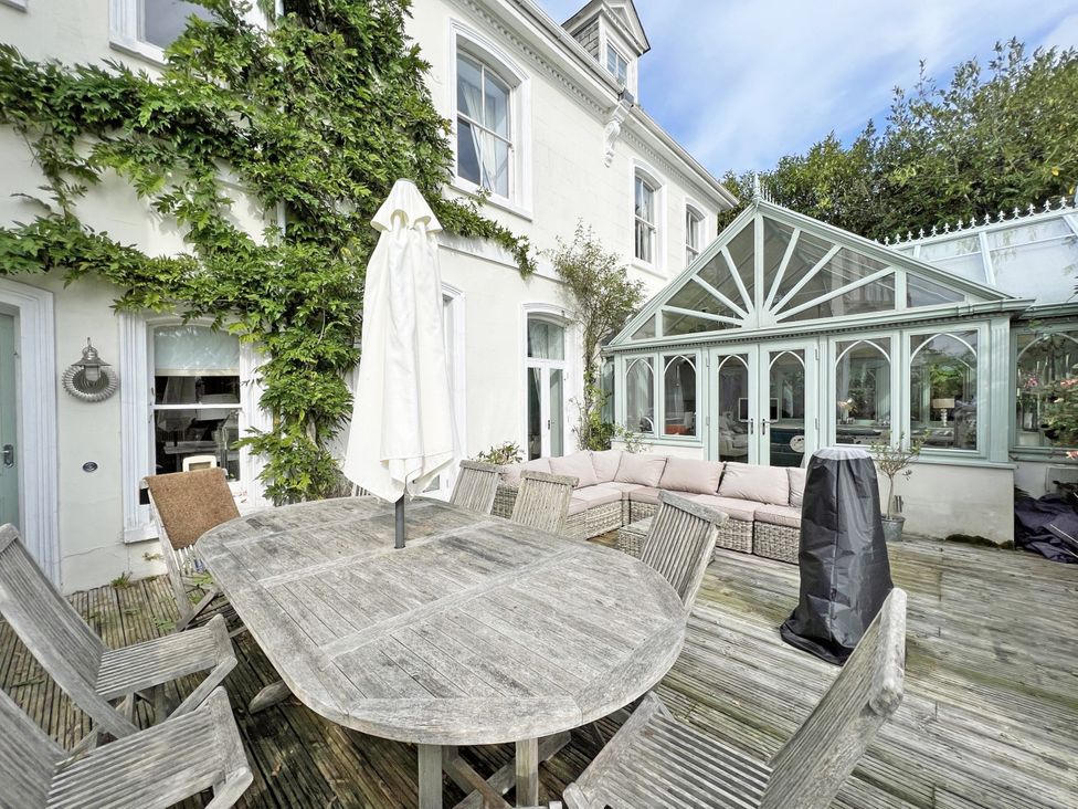 A garden with a table and chairs near a conservatory at Trenare in Truro