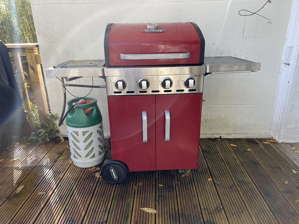 A barbecue grill with a gas cylinder on a wooden deck at Trenare in Truro
