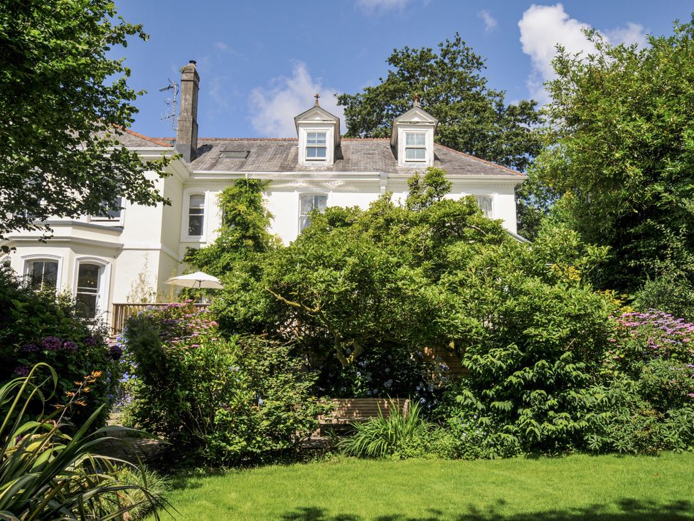 A garden with a house and greenery at Trenare in Truro