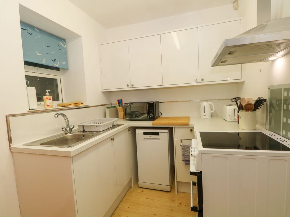 A kitchen with sink, dishwasher, and microwave at Holme Cottage in Hebden Bridge