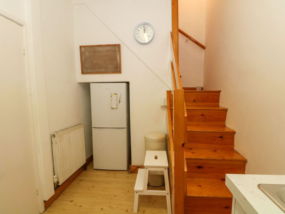 A hallway with stairs and a fridge at Holme Cottage in Hebden Bridge