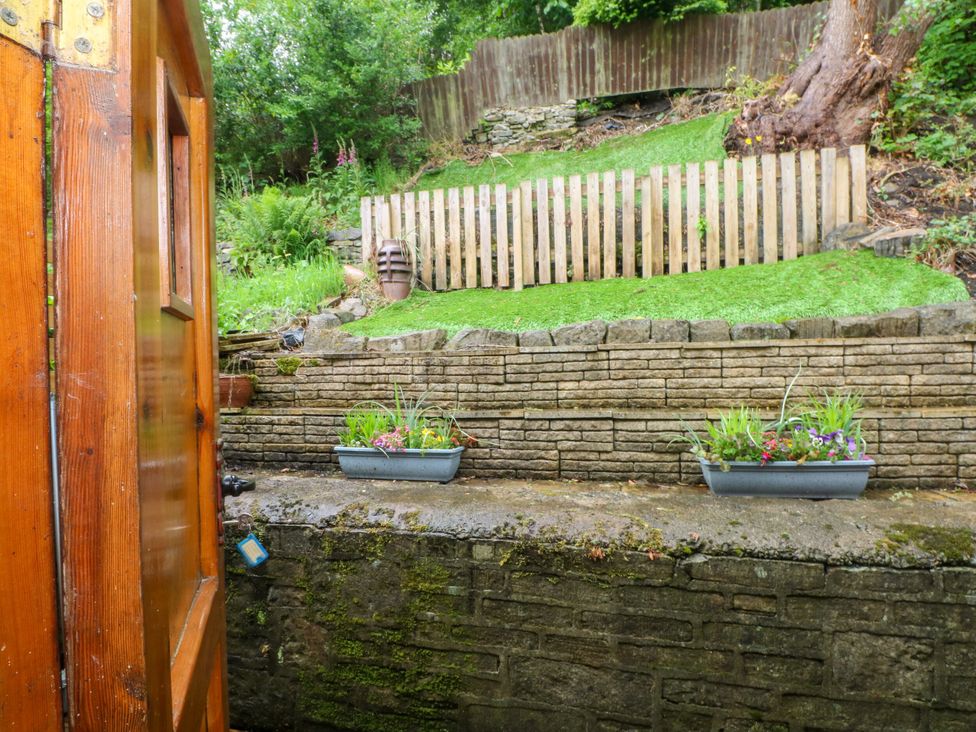 A garden with a wooden fence and planters at Holme Cottage in Hebden Bridge
