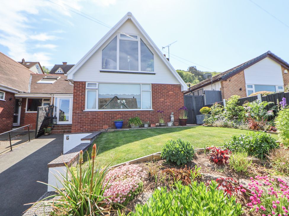 A house with a sloped roof flower beds and a lawn at 67 Pendre Avenue Prestatyn