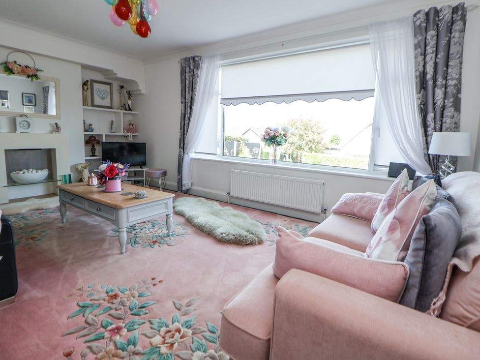 A living room with a pink sofa and floral carpet at 67 Pendre Avenue in Prestatyn