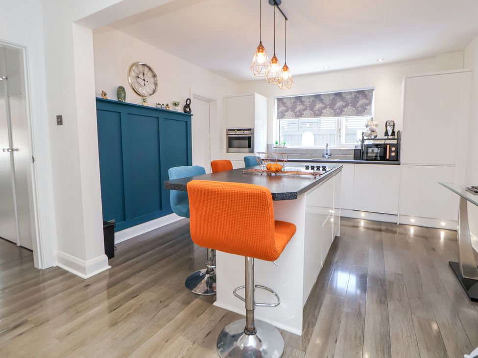 A kitchen with an island and orange and blue bar stools at 67 Pendre Avenue in Prestatyn
