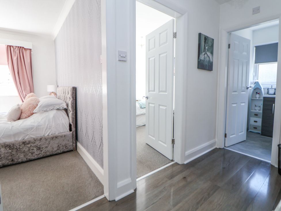 A hallway with open white doors leading to bedrooms and a bathroom at 67 Pendre Avenue Prestatyn