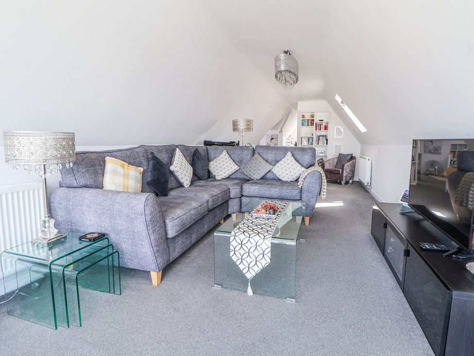 A living room with a gray sectional sofa and glass tables at 67 Pendre Avenue in Prestatyn