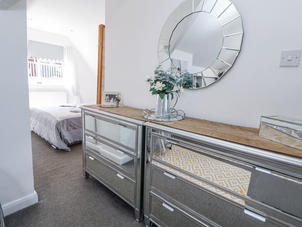 A hallway with mirrored dressers and a round mirror above at 67 Pendre Avenue in Prestatyn