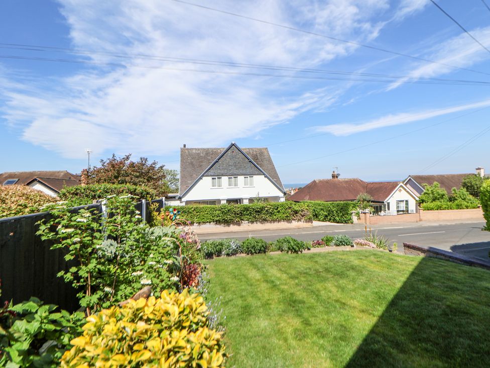 A front yard with grass and shrubs facing a street with houses at 67 Pendre Avenue in Prestatyn