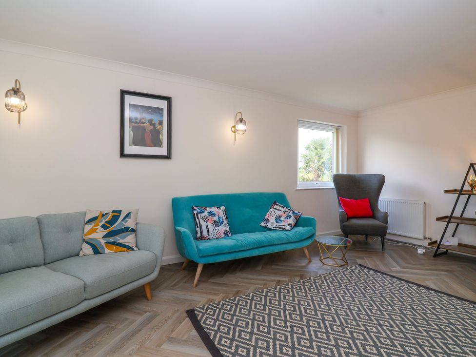 A living room with two sofas a patterned rug a window and wall lights at Hillside in Bishops Cleeve