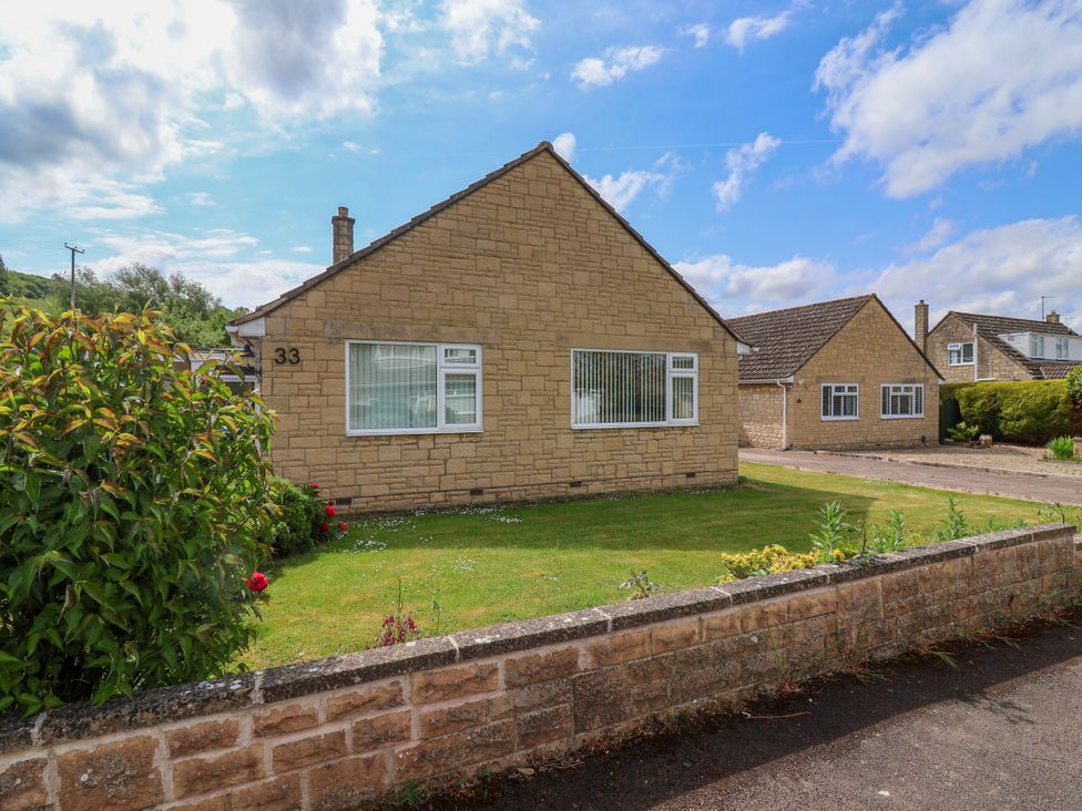 A stone bungalow with two windows and a garden surrounded by a low stone wall at Hillside in Bishops Cleeve