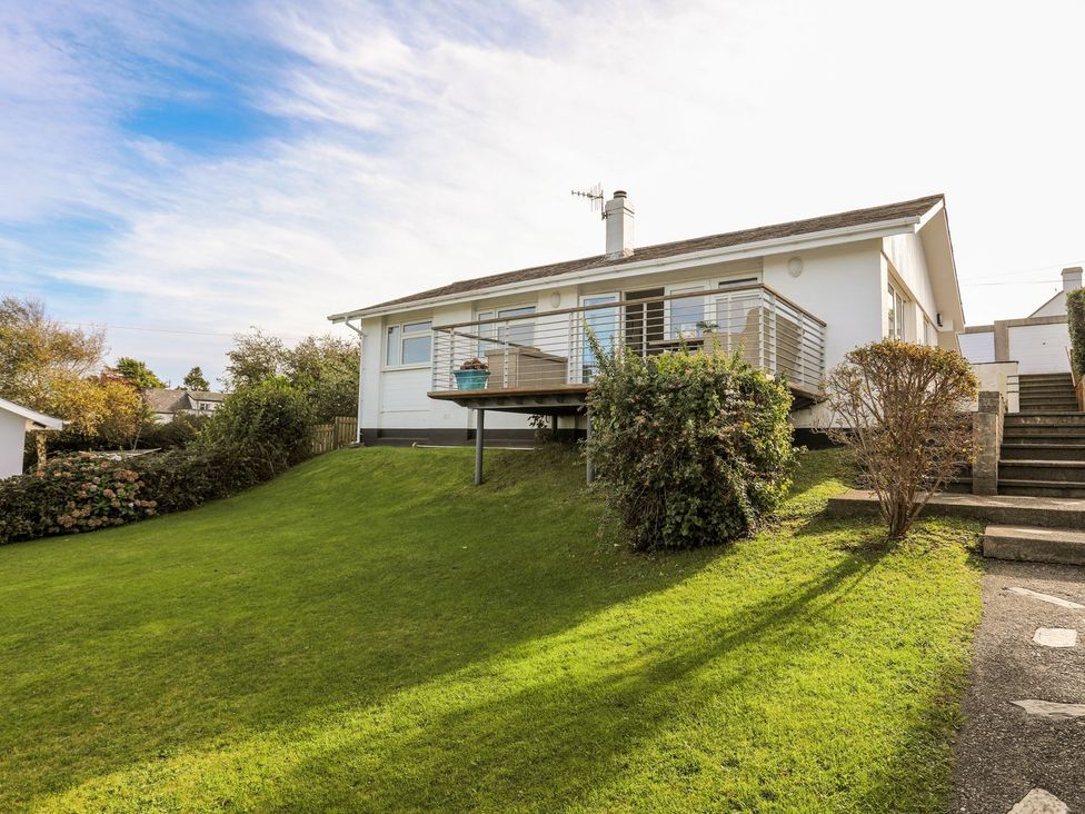 A house with a deck and grassy area at Machroes Cottage Pwllheli