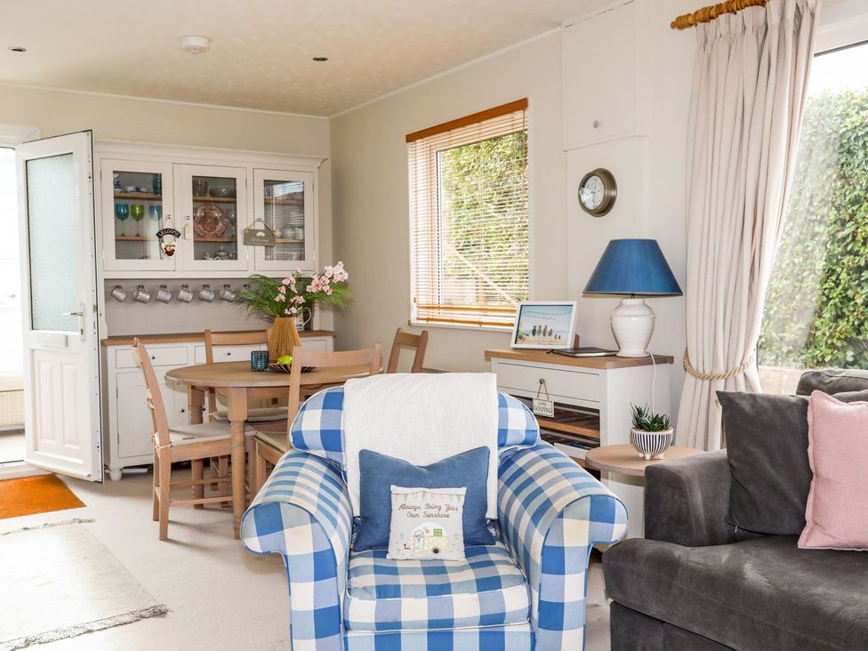 A living room with a checkered chair and table at Machroes Cottage in Pwllheli