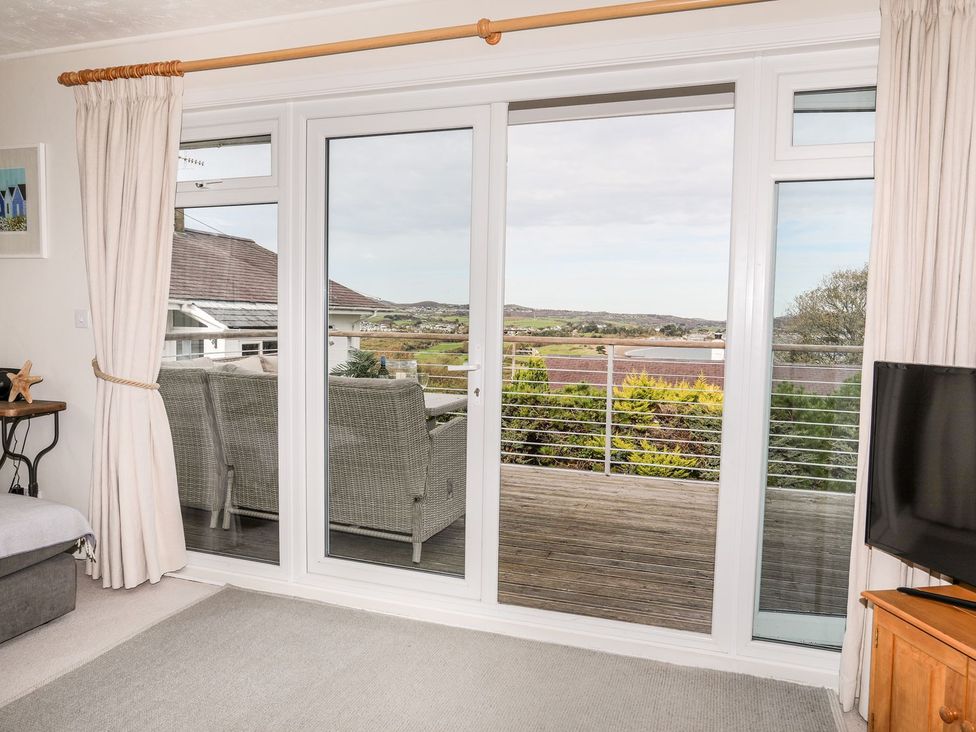 A living room with sliding doors and a television at Machroes Cottage in Pwllheli