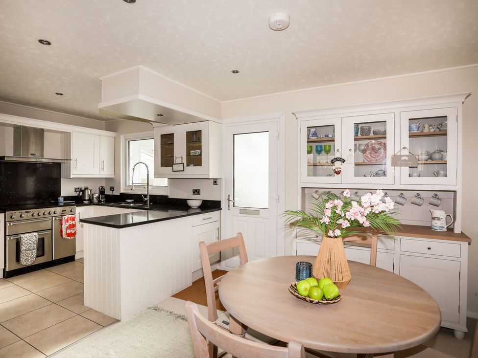 A kitchen with a dining table and kitchen cabinet at Machroes Cottage in Pwllheli