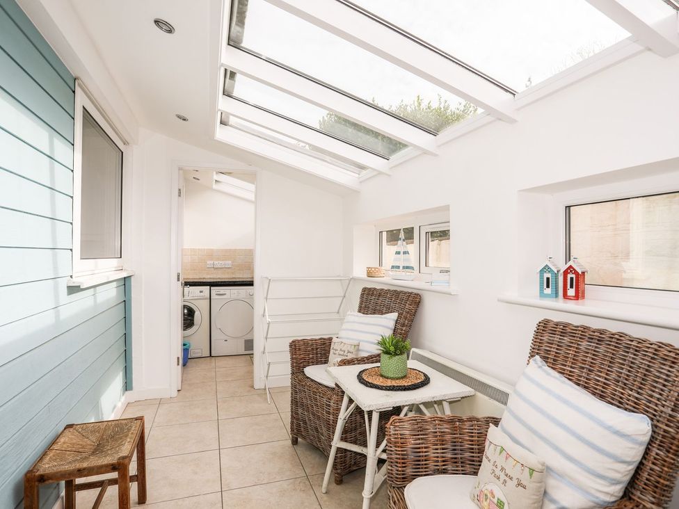 A conservatory with two chairs and a washing machine at Machroes Cottage Pwllheli