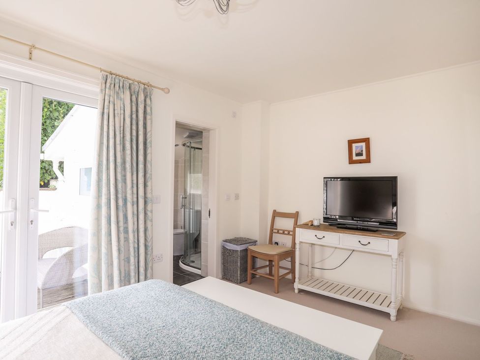 A bedroom with a television and a chair at Machroes Cottage in Pwllheli