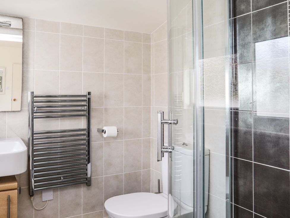 A bathroom with a shower, sink and toilet at Machroes Cottage in Pwllheli