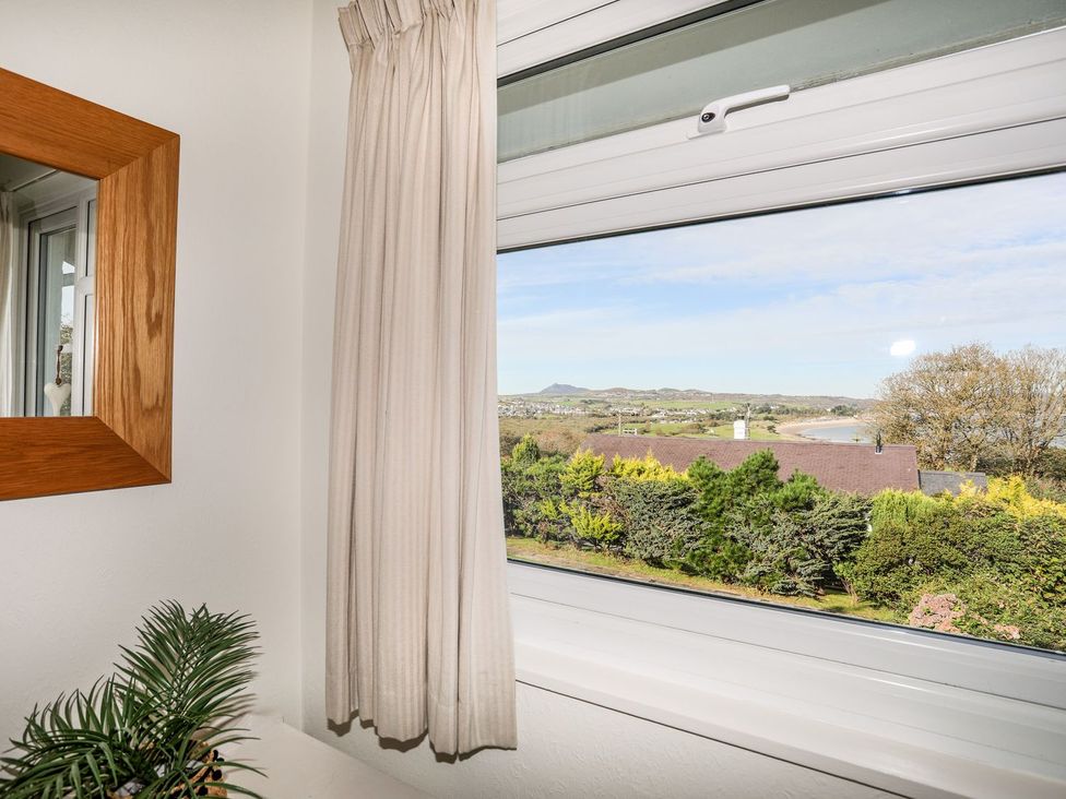 A window with a view and a curtain at Machroes Cottage Pwllheli