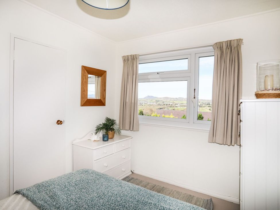 A bedroom with a bed and window view at Machroes Cottage in Pwllheli
