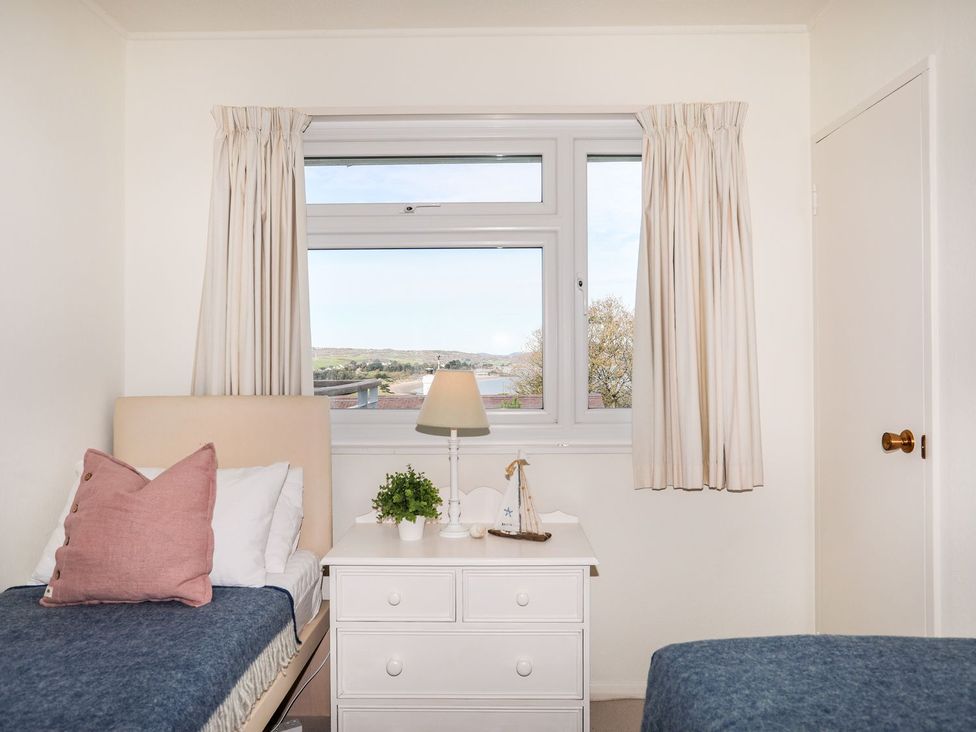 A bedroom with beds and a window at Machroes Cottage Pwllheli