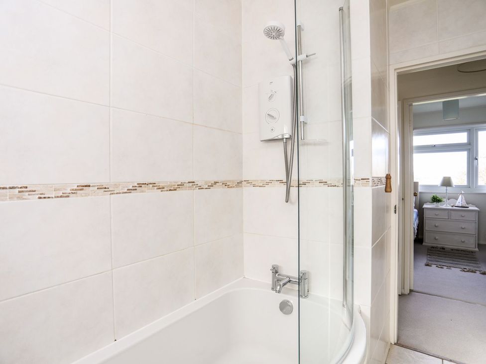 A bathroom with a bathtub and shower at Machroes Cottage Pwllheli