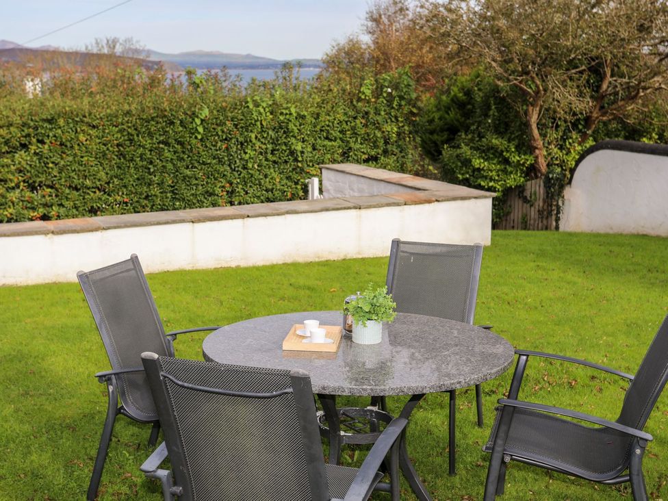 A round table with chairs in a garden at Machroes Cottage in Pwllheli