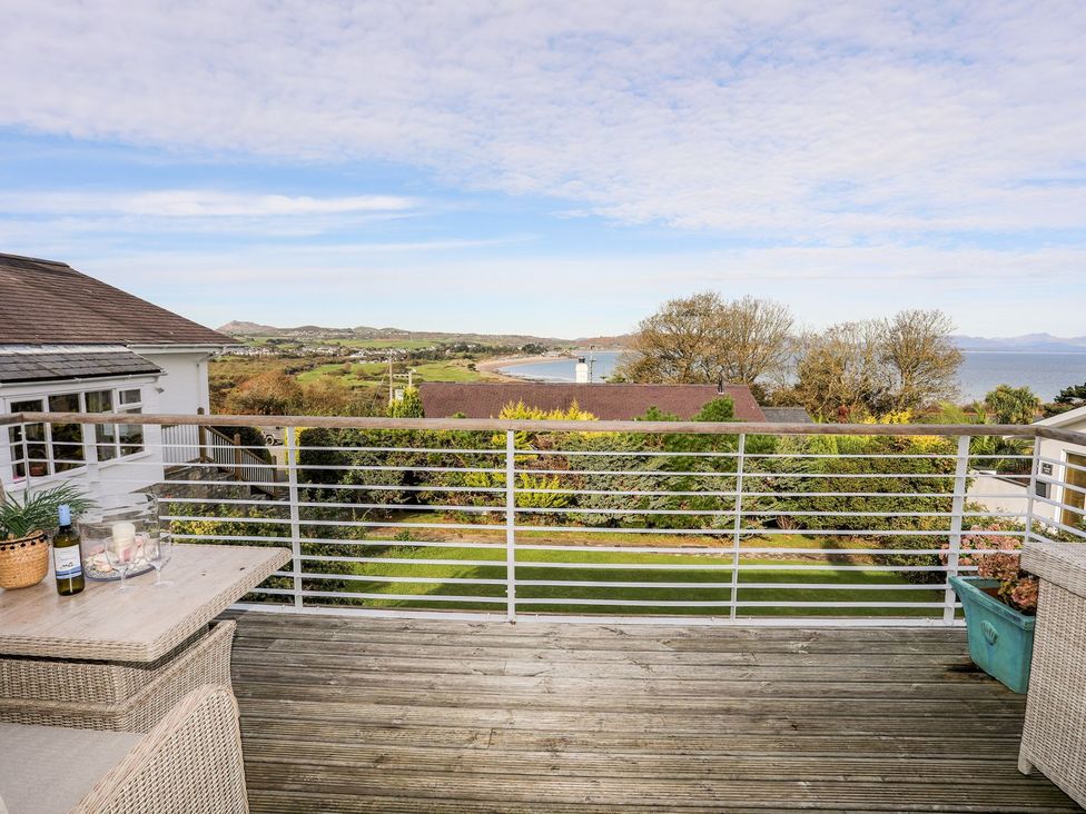 A deck with outdoor furniture and a view of the sea at Machroes Cottage Pwllheli