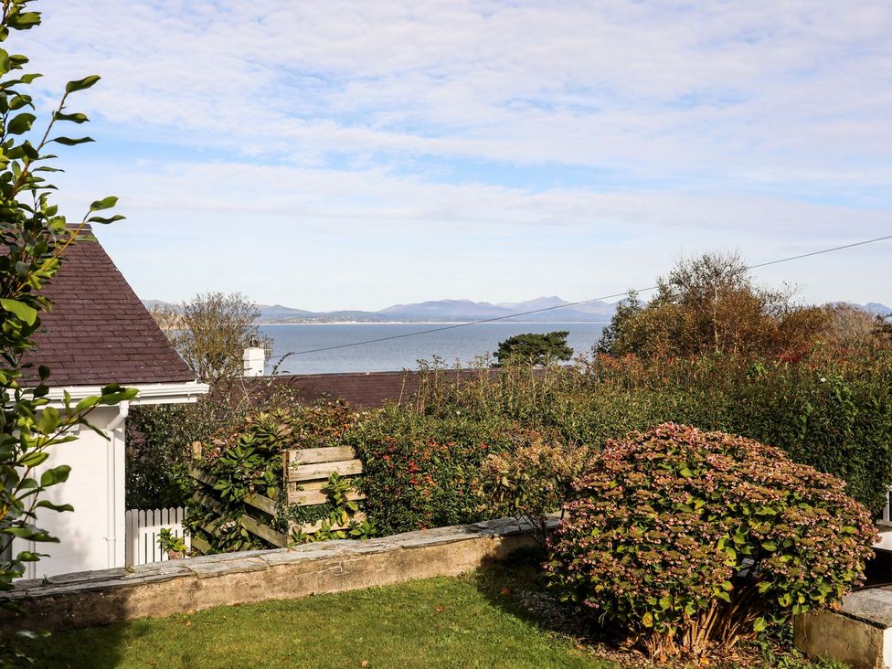 A garden view with ocean and mountains at Machroes Cottage Pwllheli