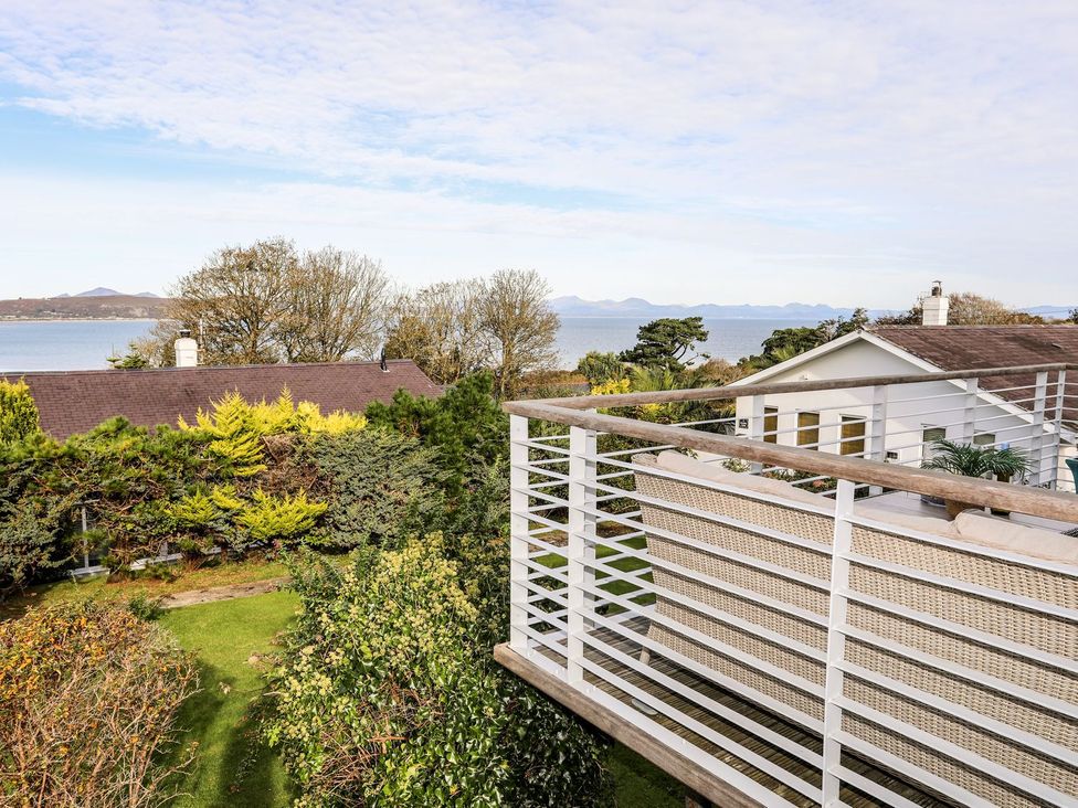 A view of the sea and gardens from a balcony at Machroes Cottage in Pwllheli