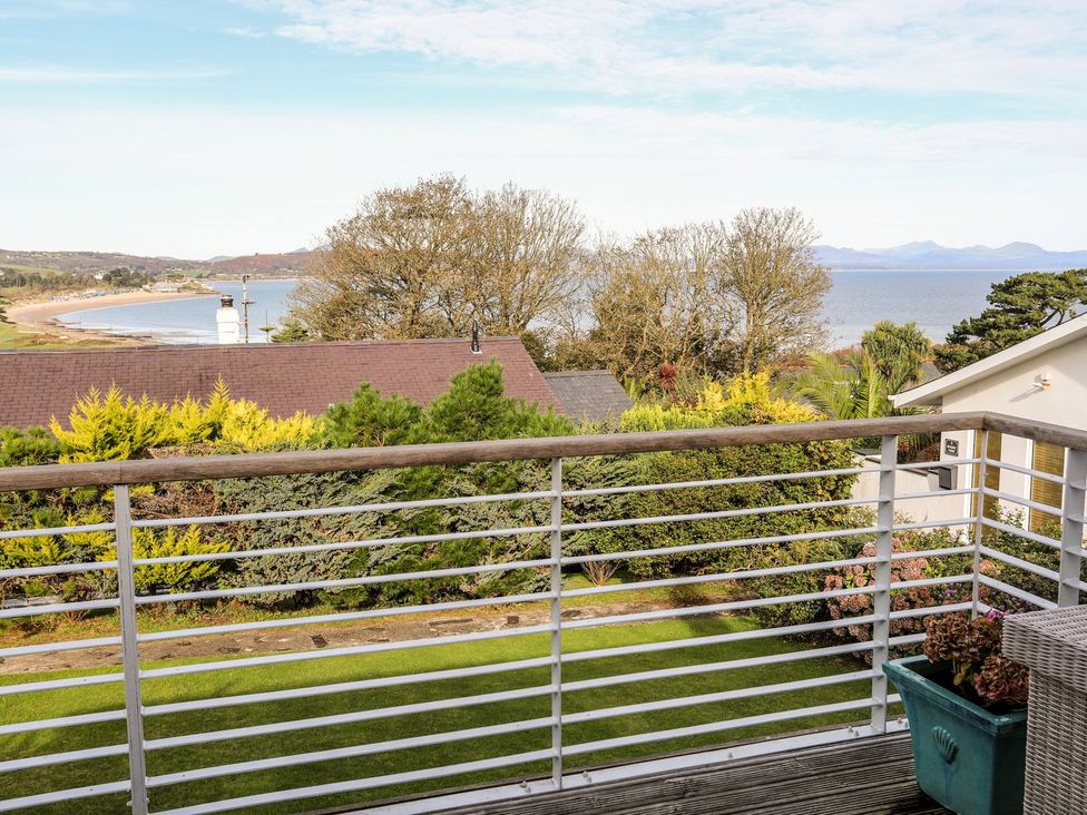 A balcony view overlooking the sea and surrounding houses at Machroes Cottage Pwllheli
