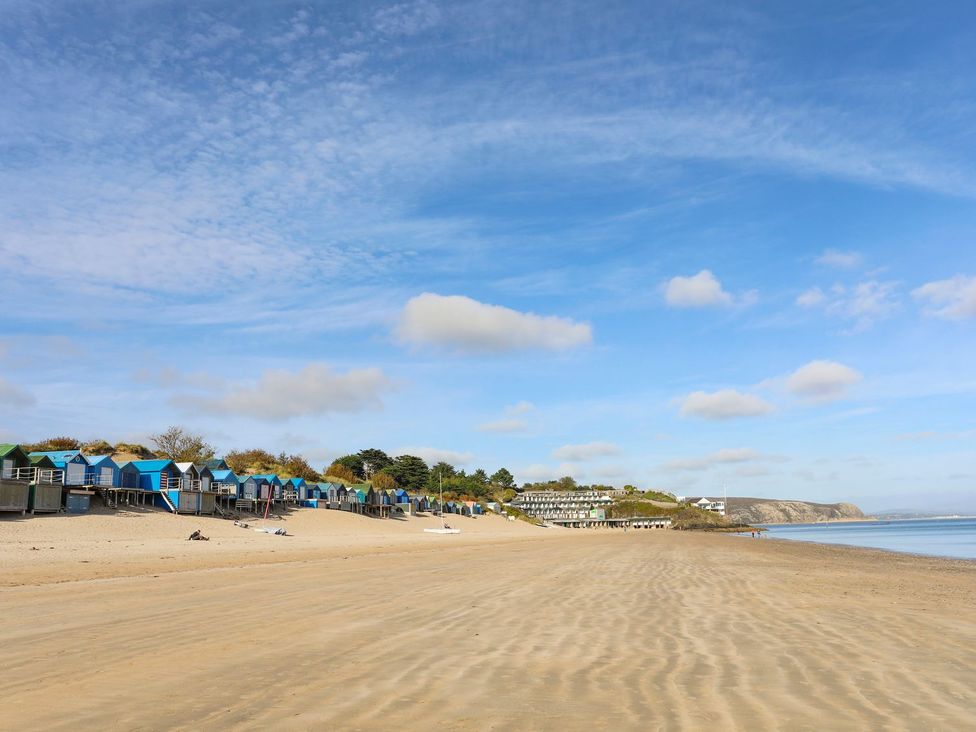 A beach with beach huts and a calm sea at Machroes Cottage in Pwllheli