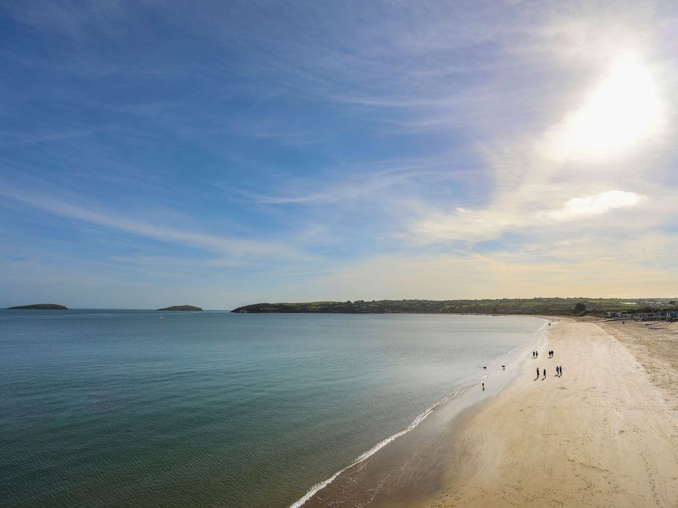 A beach with people walking along the shore at Machroes Cottage Pwllheli
