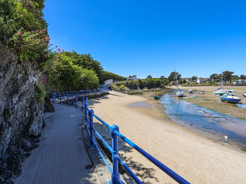 A path beside the water with boats along the shore at Machroes Cottage in Pwllheli