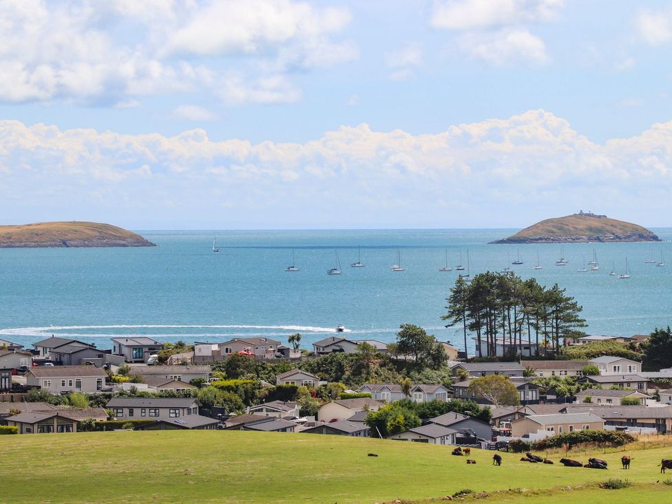 A view of houses and water with boats and islands at Machroes Cottage Pwllheli
