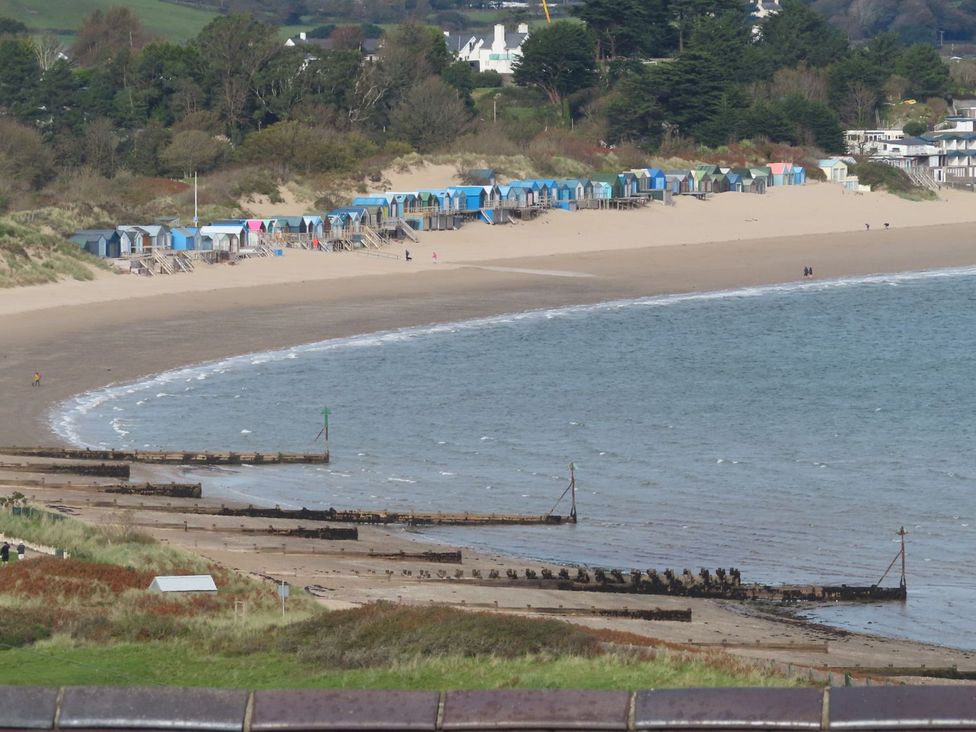 A beach with colorful beach huts and a view of the sea at Machroes Cottage Pwllheli