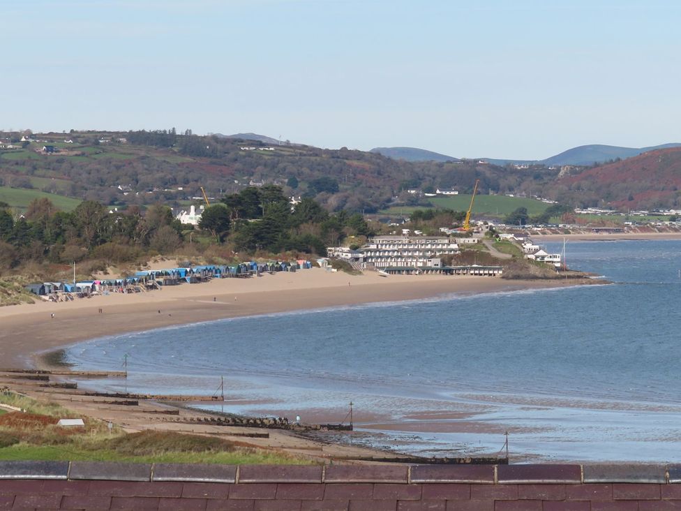 A beach with huts and water at Machroes Cottage Pwllheli