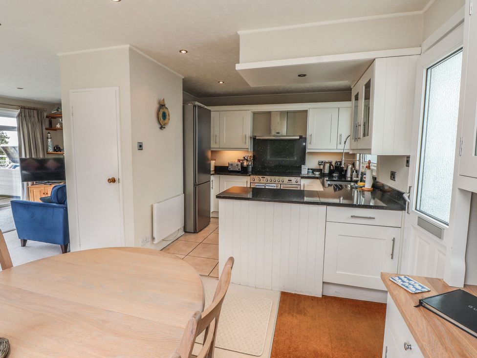 A kitchen with a dining table and refrigerator at Machroes Cottage Bwlchtocyn near Abersoch