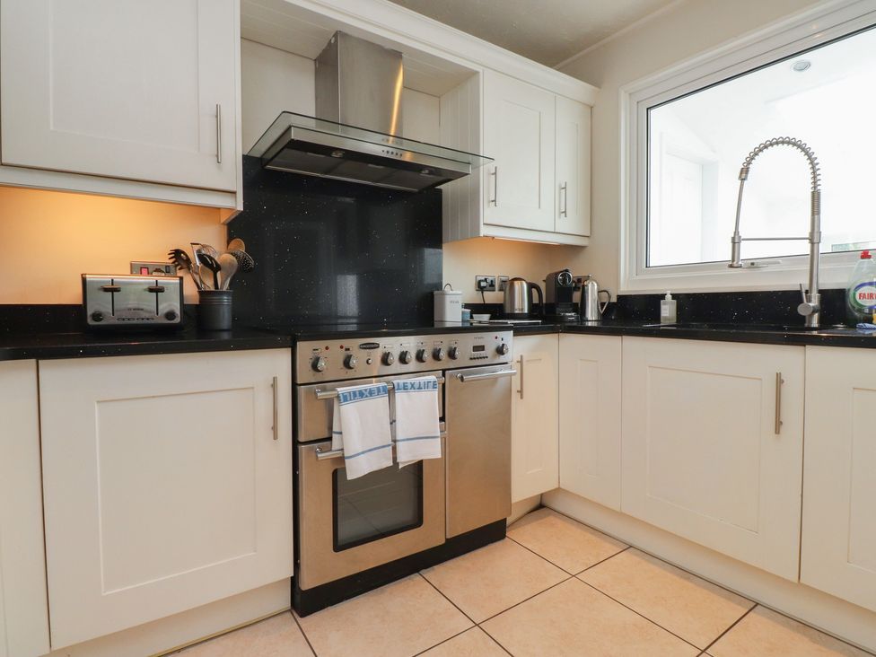 A kitchen with cabinets, an oven, a sink, and various kitchen appliances at Machroes Cottage in Bwlchtocyn near Abersoch